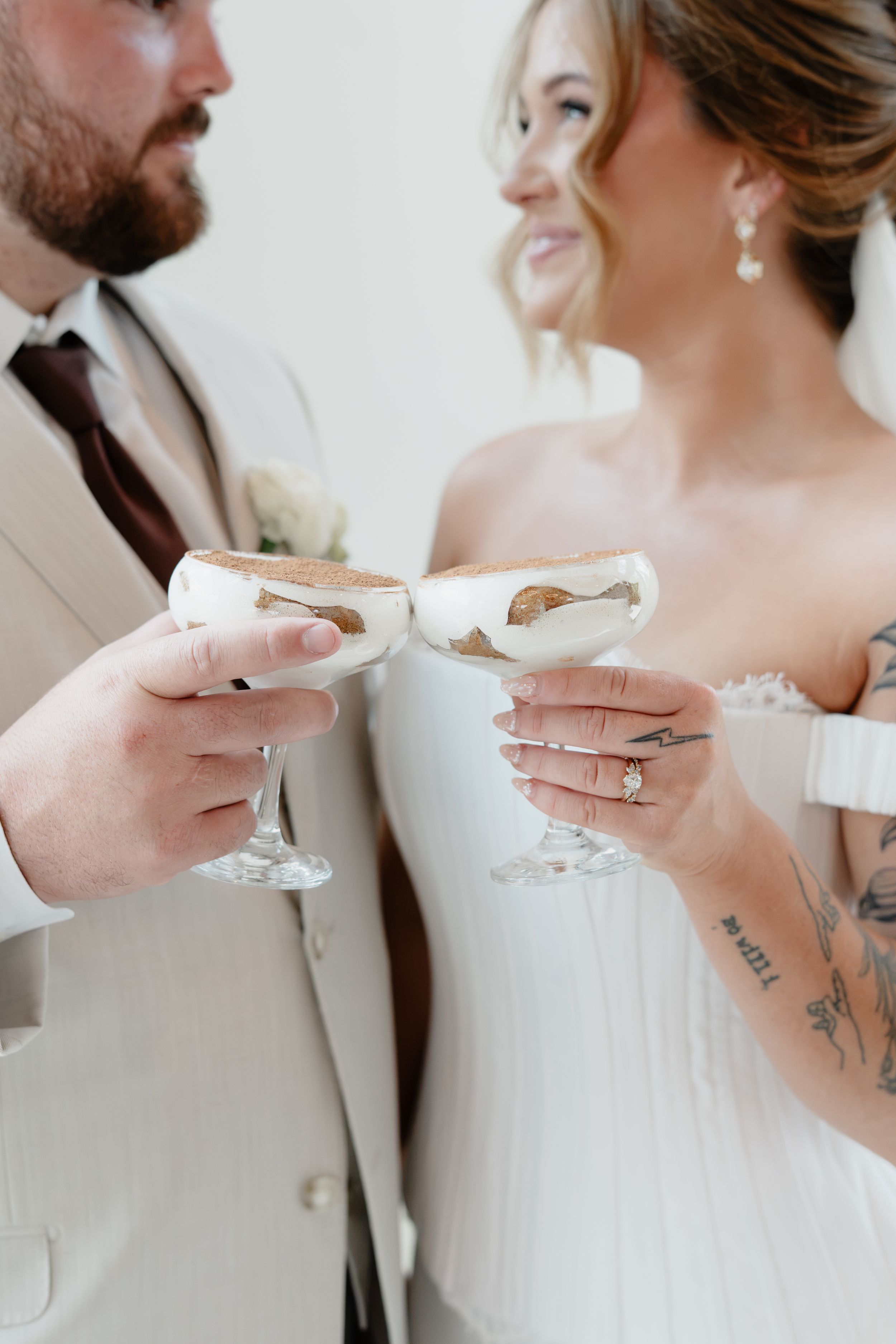 Bride and groom toasting with elegant cocktail glasses at their wedding celebration.
