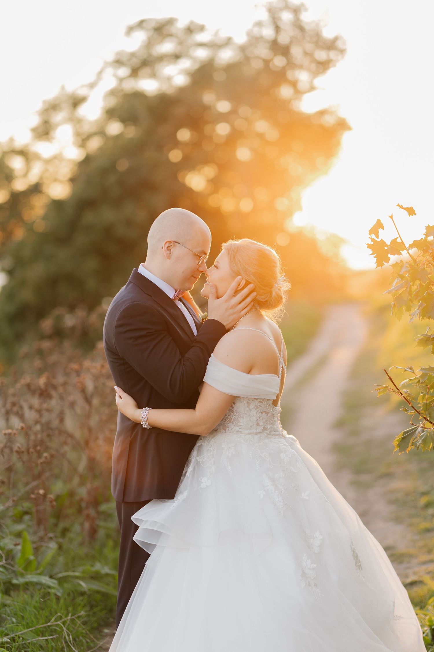Wedding couple shares intimate moment at sunset among vineyard foliage.