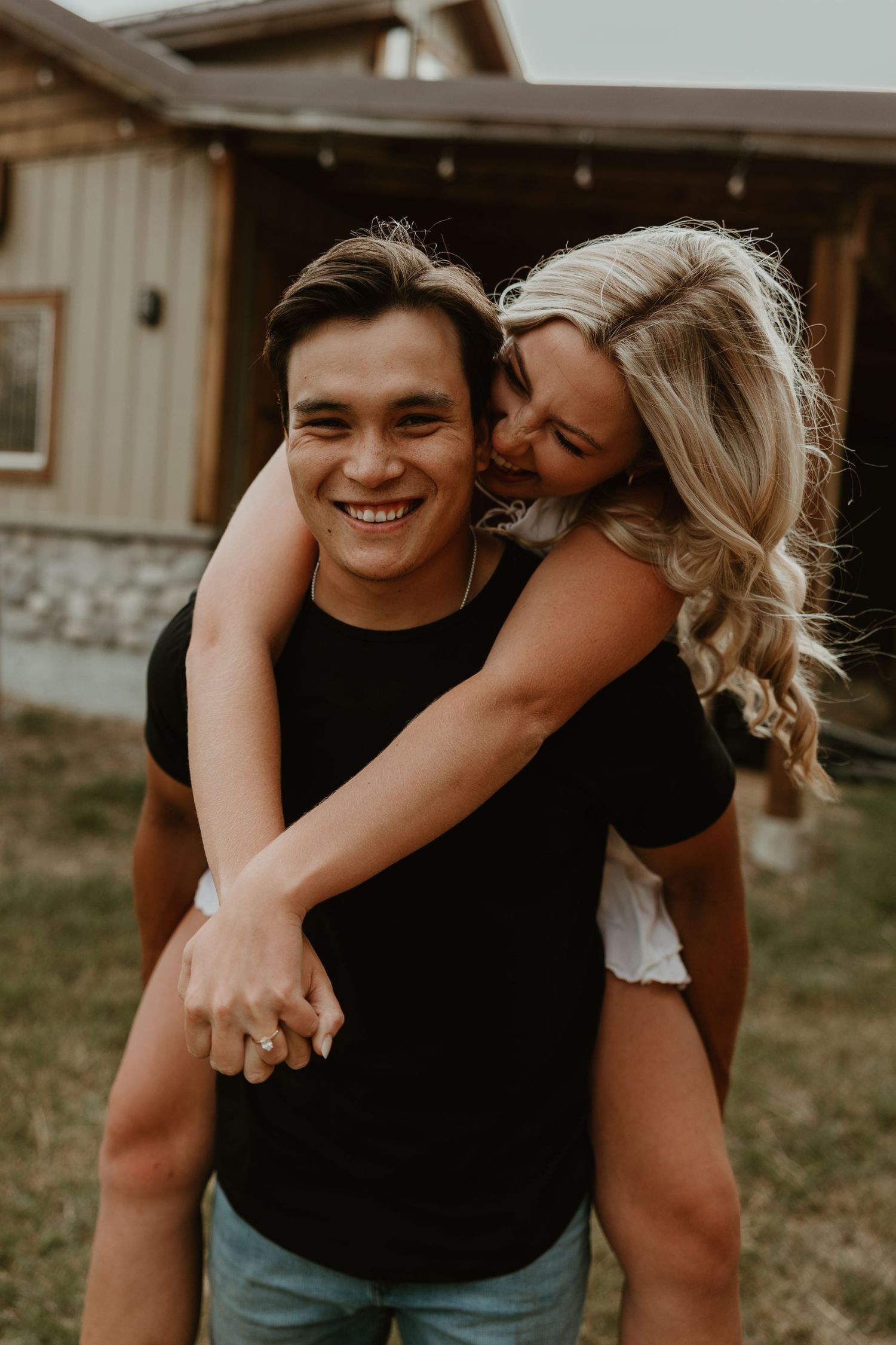 Couple sharing playful embraces during casual outdoor photo session.