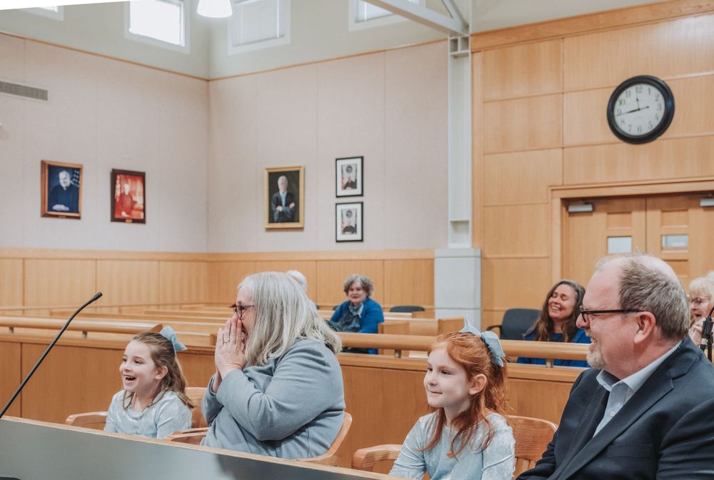 An adoptive mother smiles with enthusiam as her daughter is officially adopted during their family court hearing.