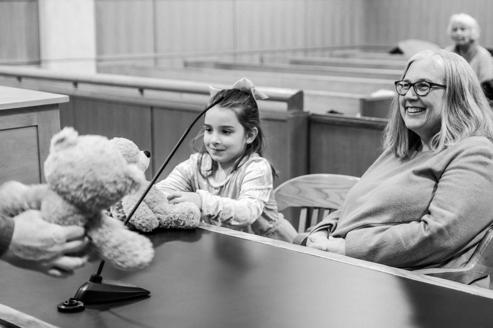 A young girl is given a stuffed congradualatory teddy bear during her adoption court date.