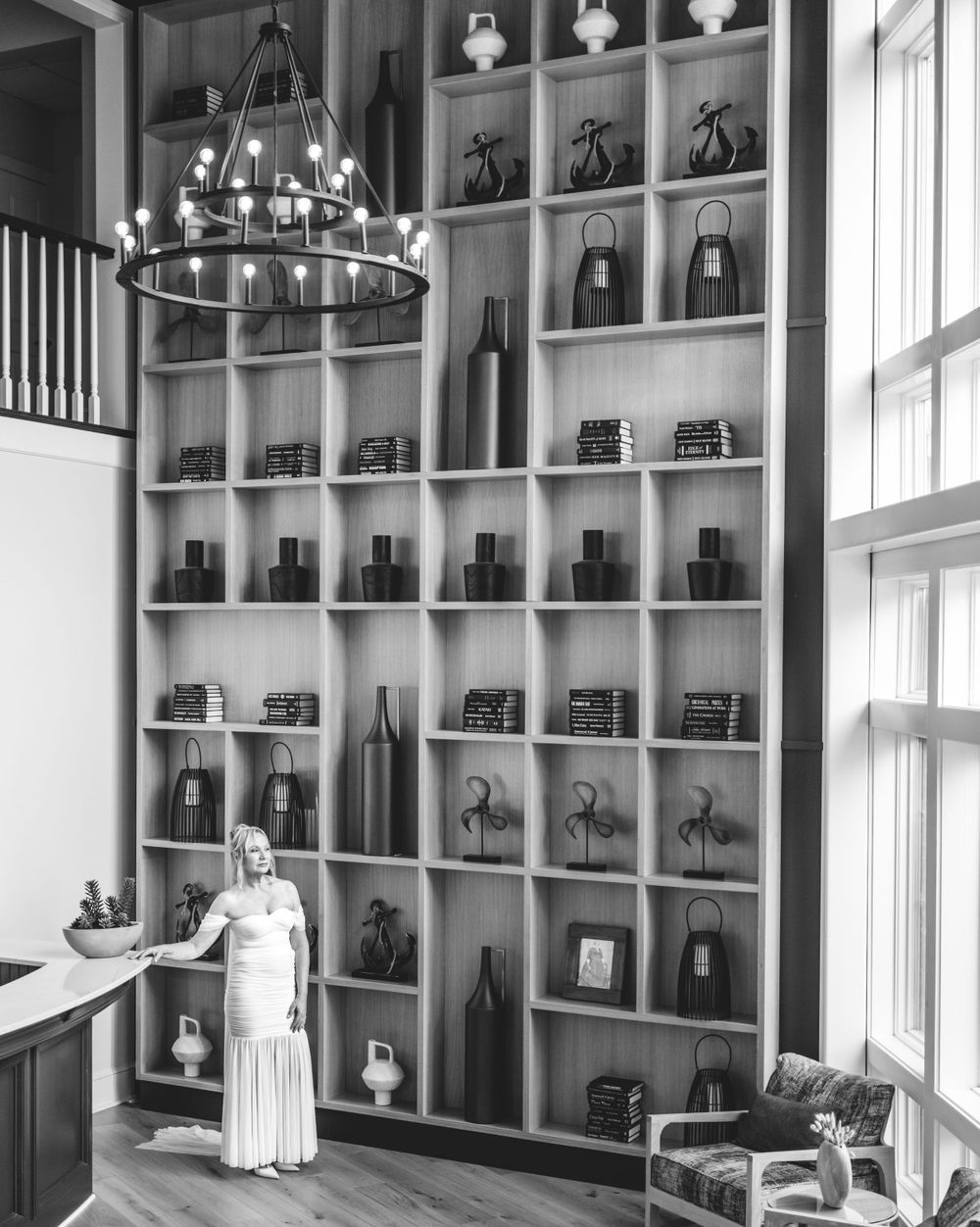 A vintage black and white photo showing a tall display wall with shelves filled with antique cameras and equipment.