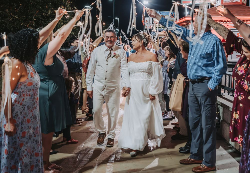 Wedding guests form an archway as newlyweds walk underneath during an outdoor celebration at the Songo River Queen in Naples, Maine.