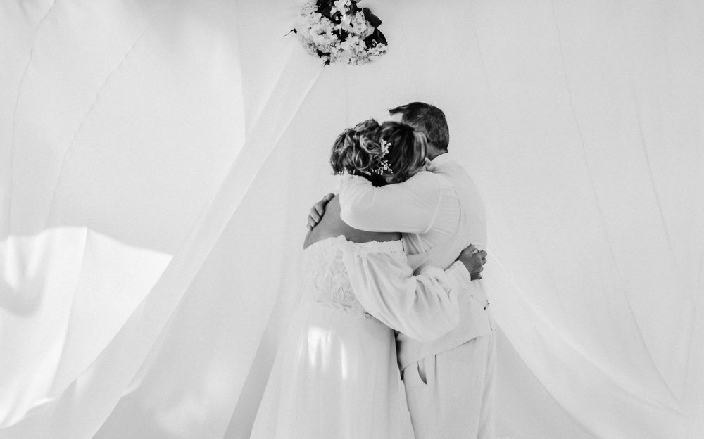 A bride in a flowing white dress hugs the groom following their ceremony aboard the Songo River Queen in Naples, Maine.