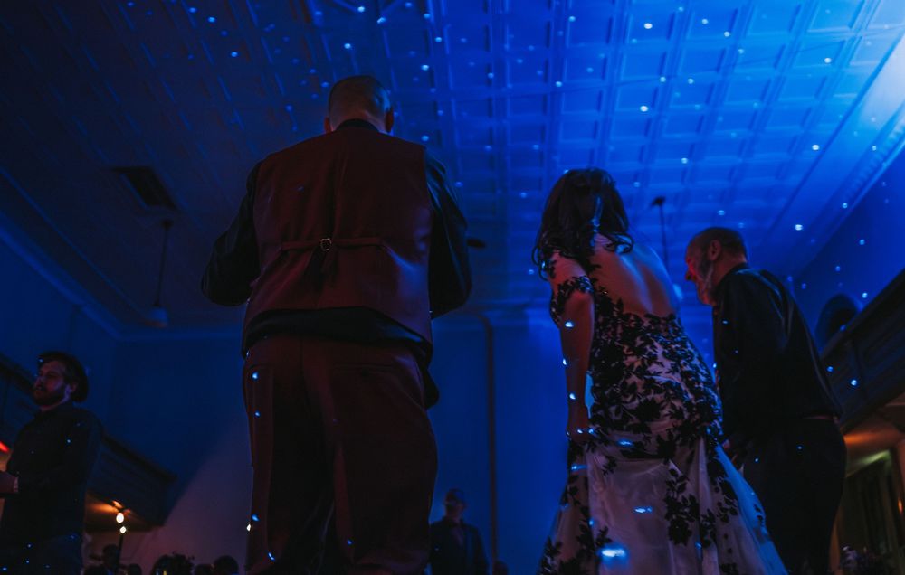 A nighttime scene shows illuminated blue lighting effects and silhouettes of people at an entertainment venue.