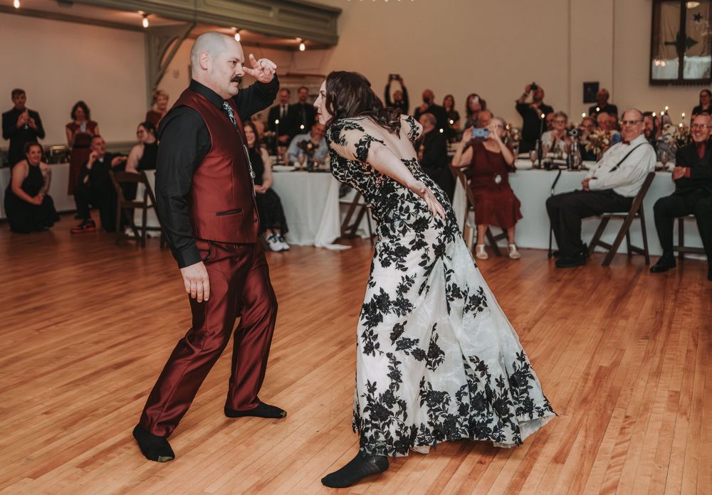 Dancers perform graceful movements on a wooden dance floor while guests watch from tables in the background.
