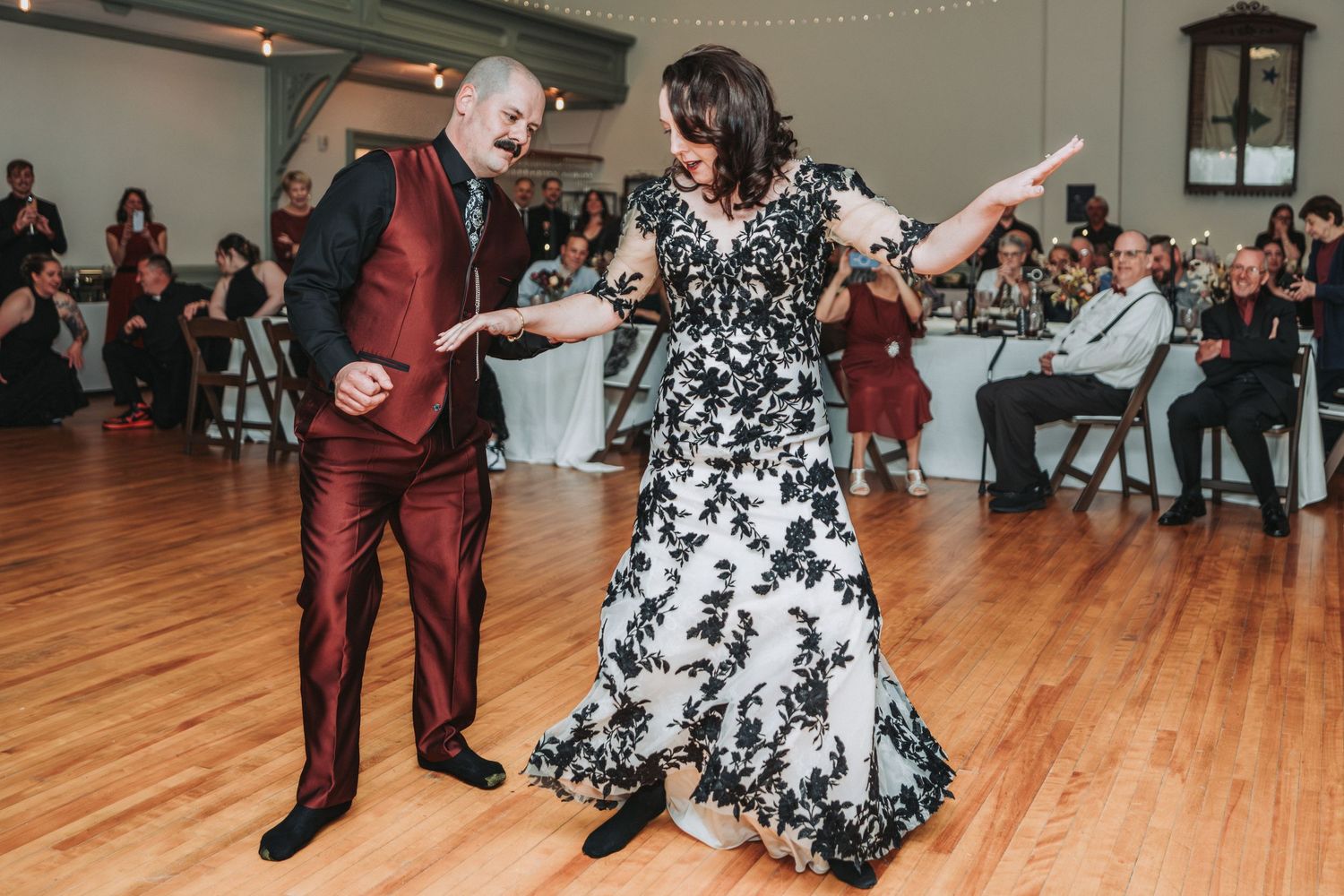 Dancers perform energetic swing dance moves on a wooden dance floor at a social gathering event.
