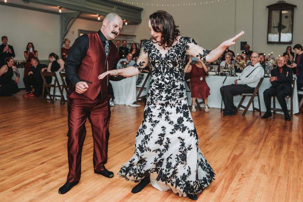 Dancers perform energetic swing dance moves on a wooden dance floor at a social gathering event.