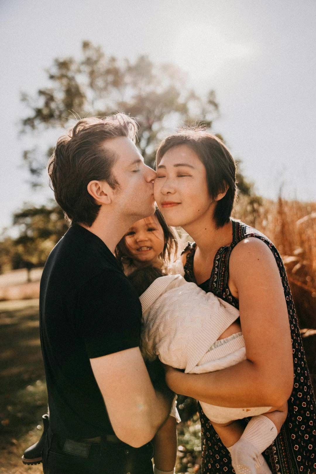 A tender family moment captured outdoors in warm sunlight showing affection and joy together.