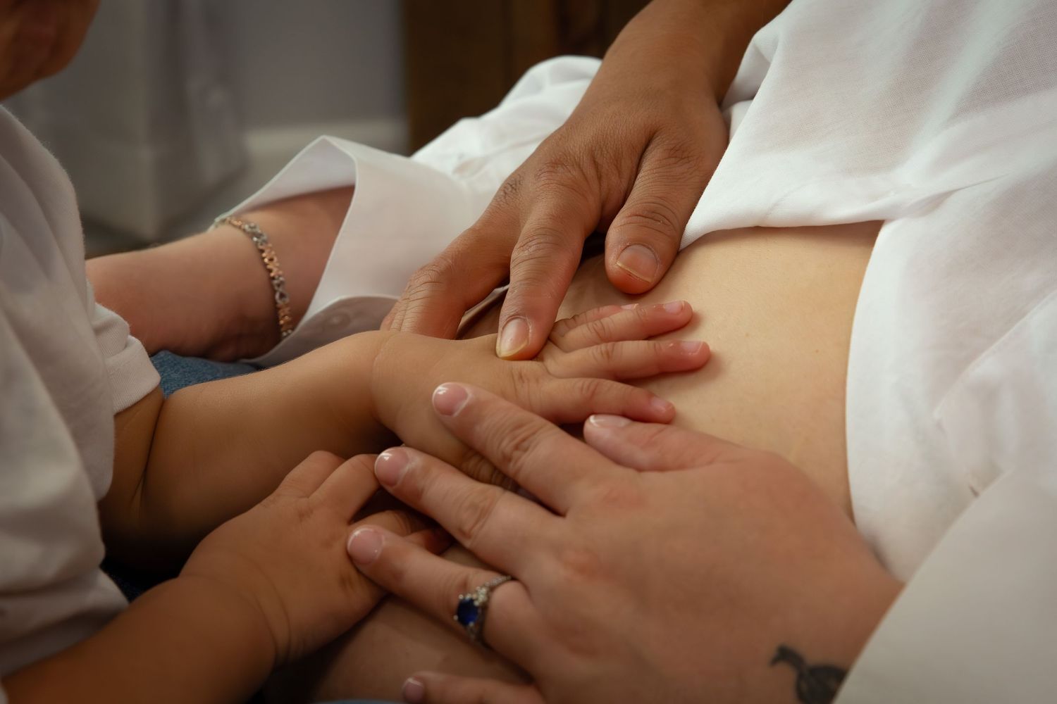 Multiple hands performing massage therapy and bodywork on a person lying on a white treatment table during a healing session.