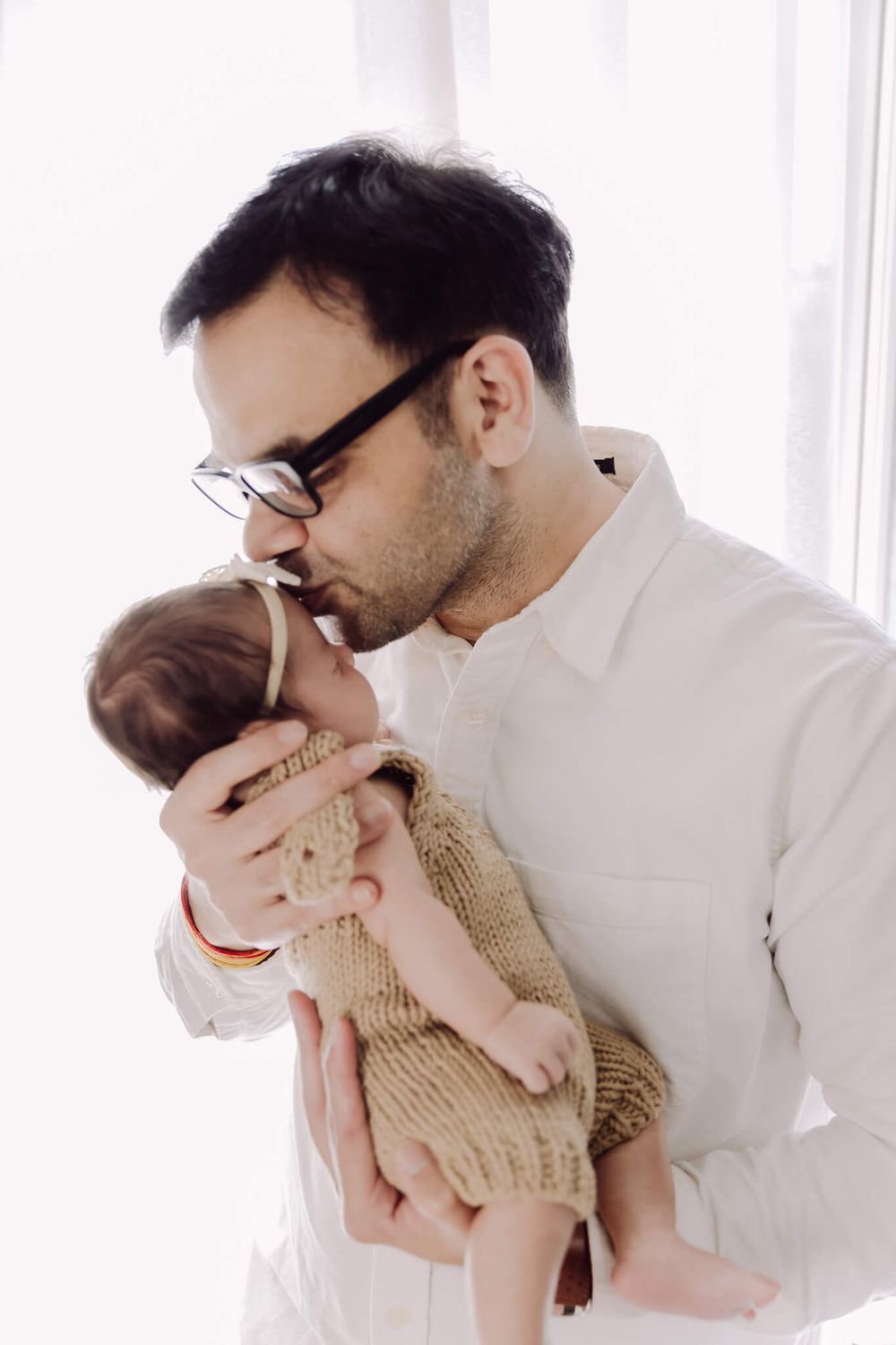 Dad holding newborn close during lifestyle family shoot in Bay Area living room