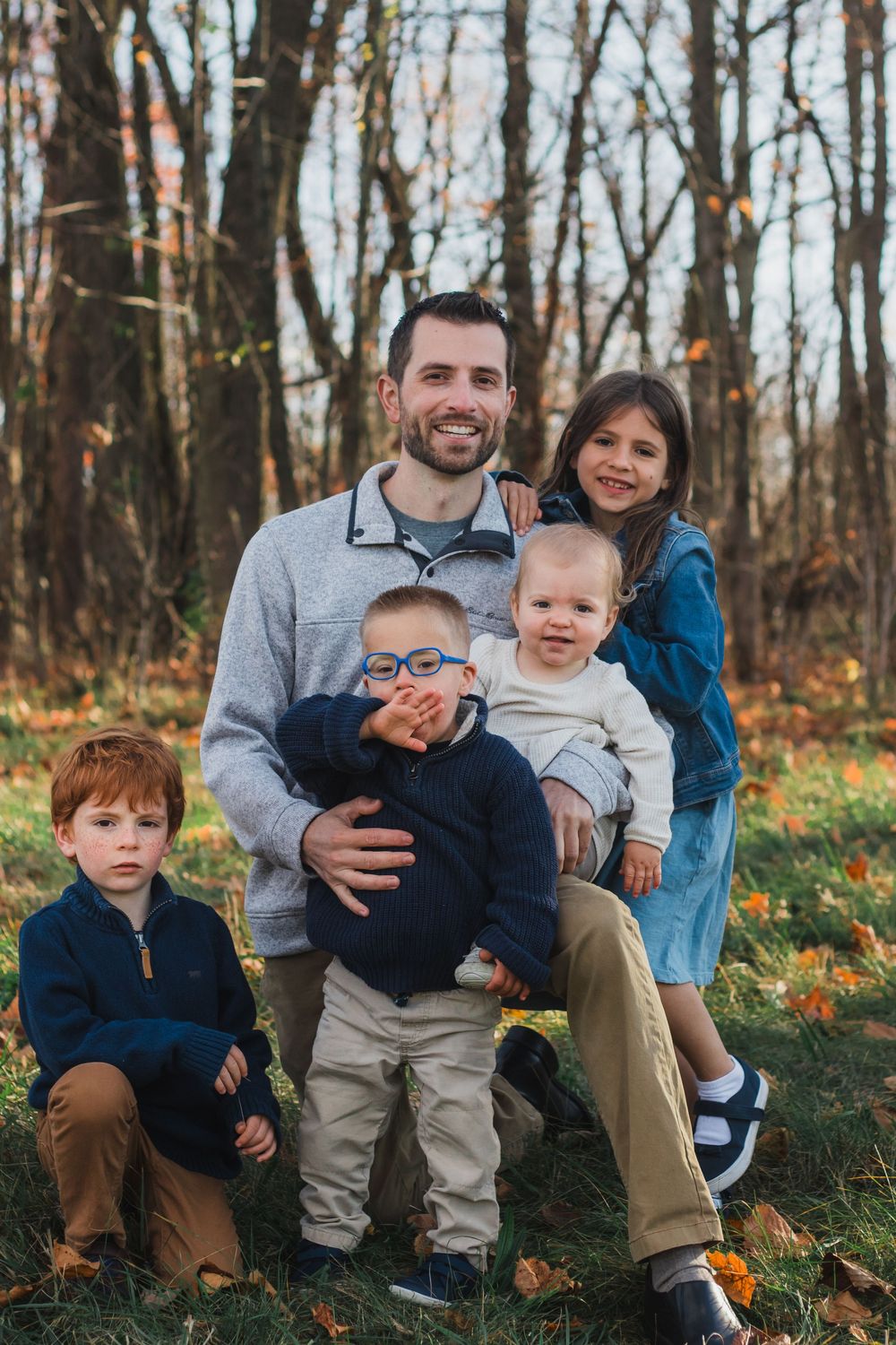 Father posing with four children in colorful autumn woodland park.