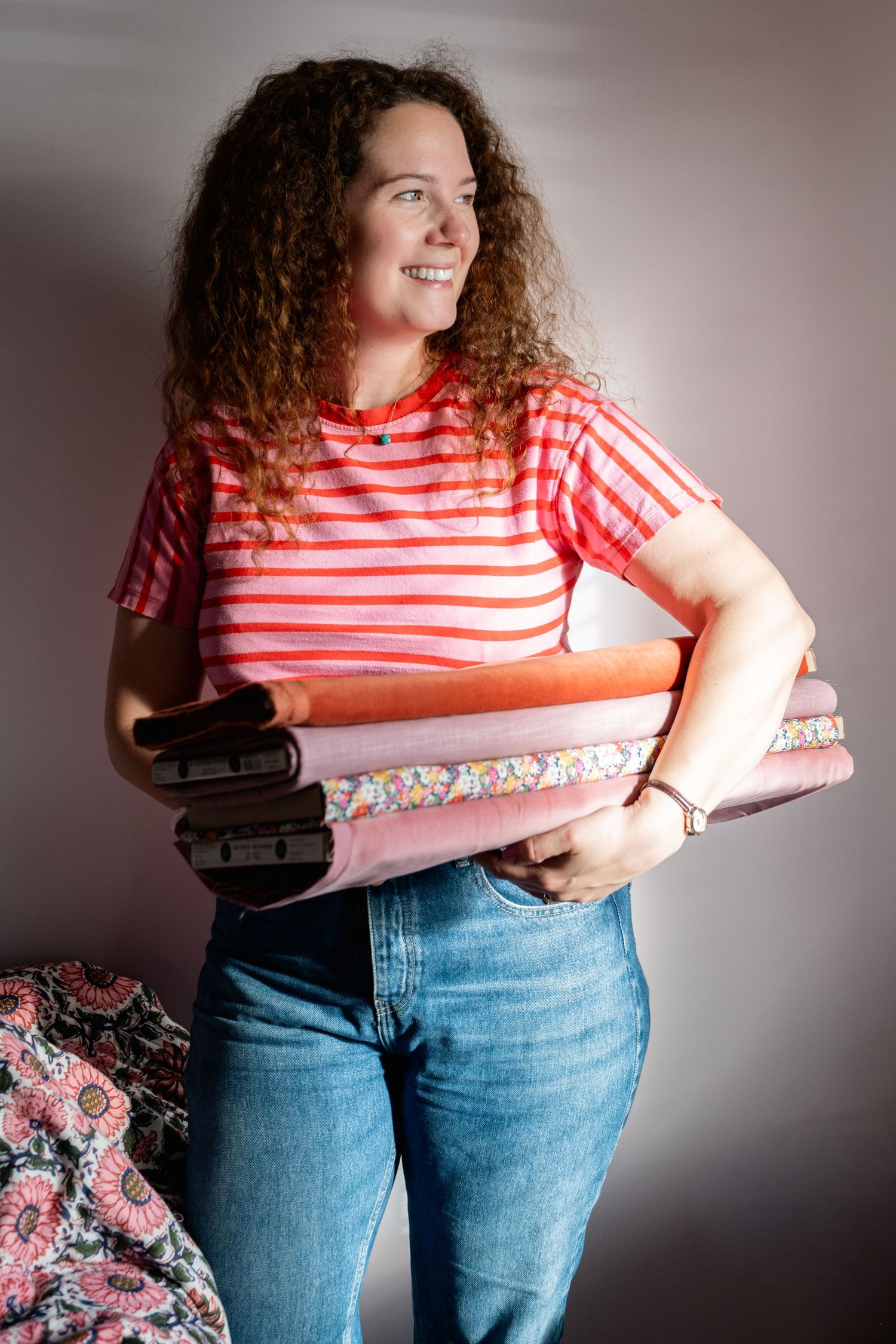 Portrait brand photo. Female interior designer in olive shirt and jeans leaning against an open door in a modern home interior.