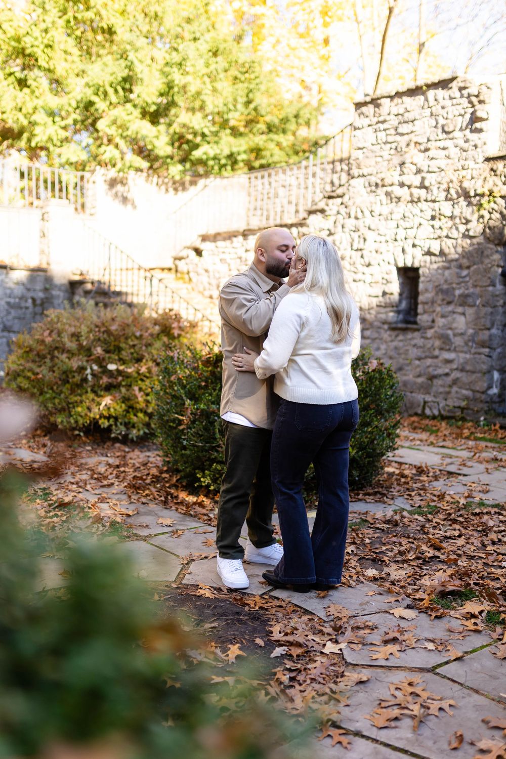 A tender autumn moment between a couple among stone walls and fallen leaves.