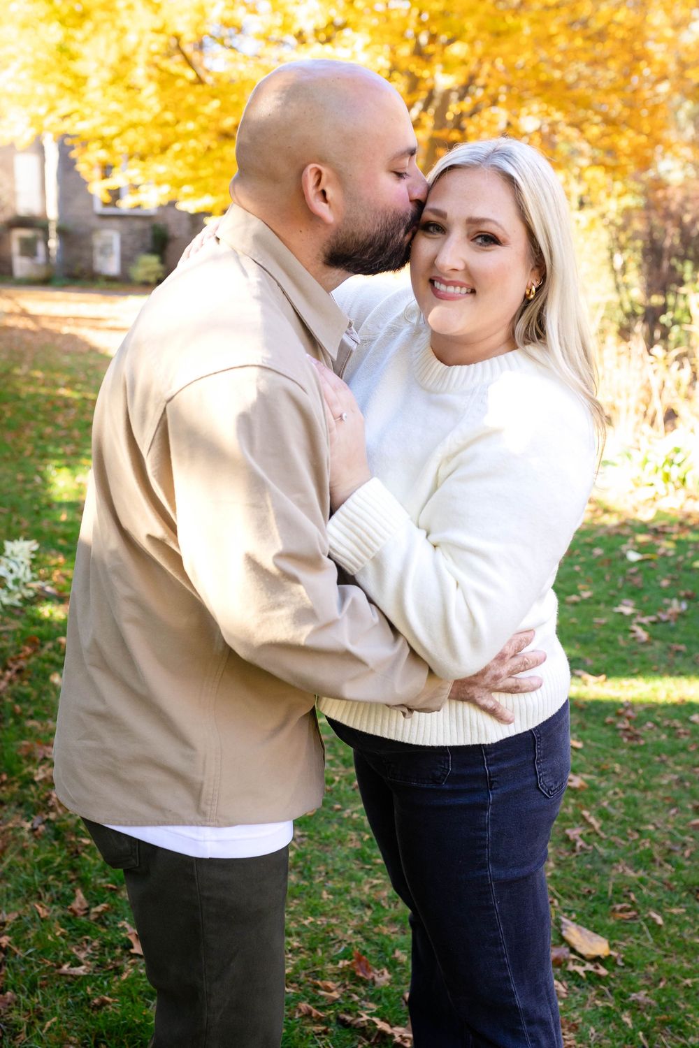 A sweet embrace shared outdoors with fall colors in the background.