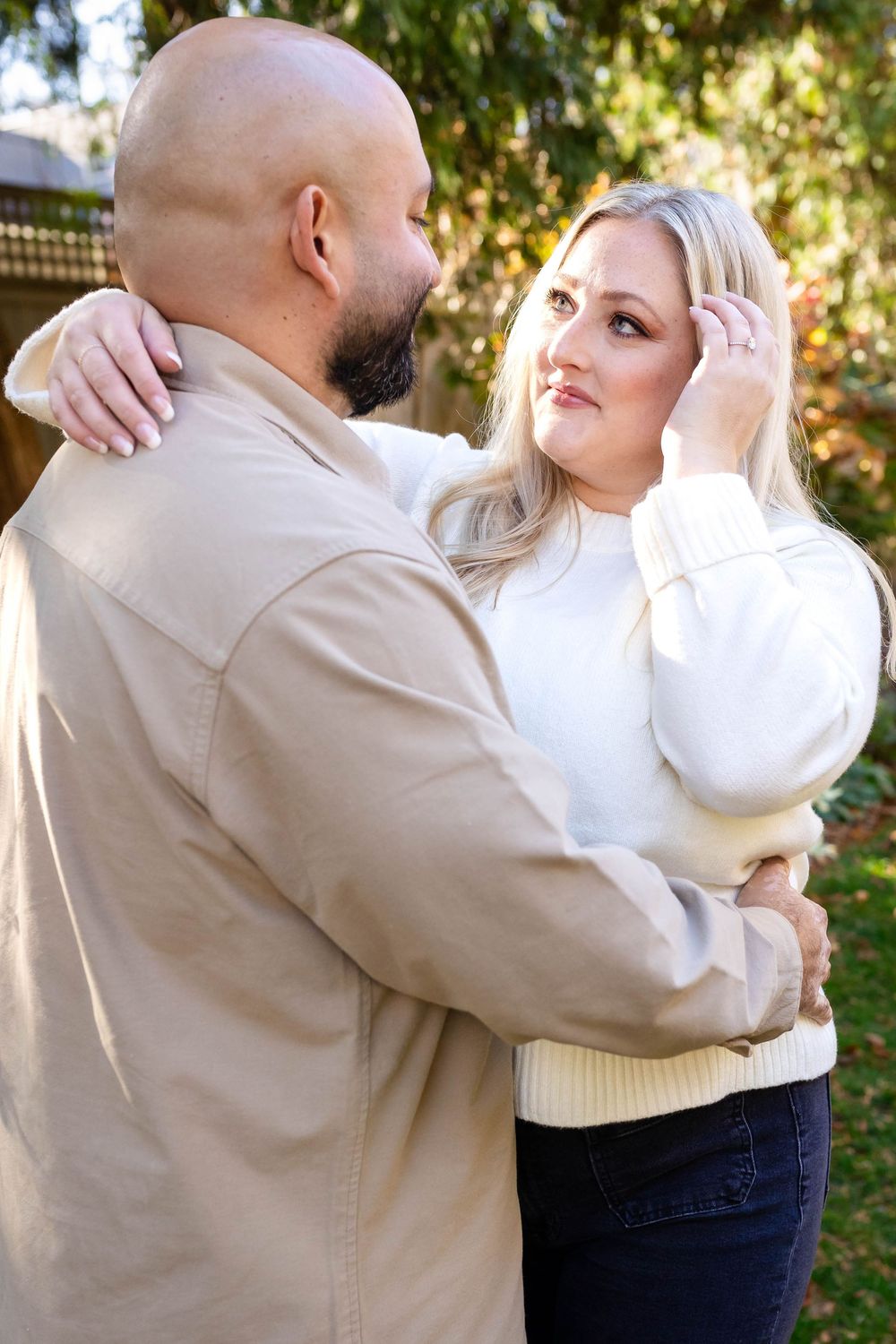 A couple shares an intimate moment together outdoors with autumn foliage in the background.