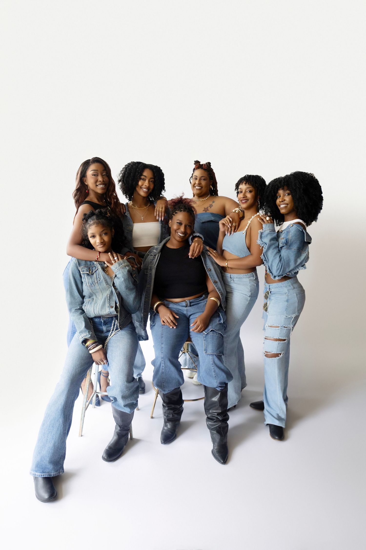Studio portrait of group in earth tones against brown background showing natural expressions.
