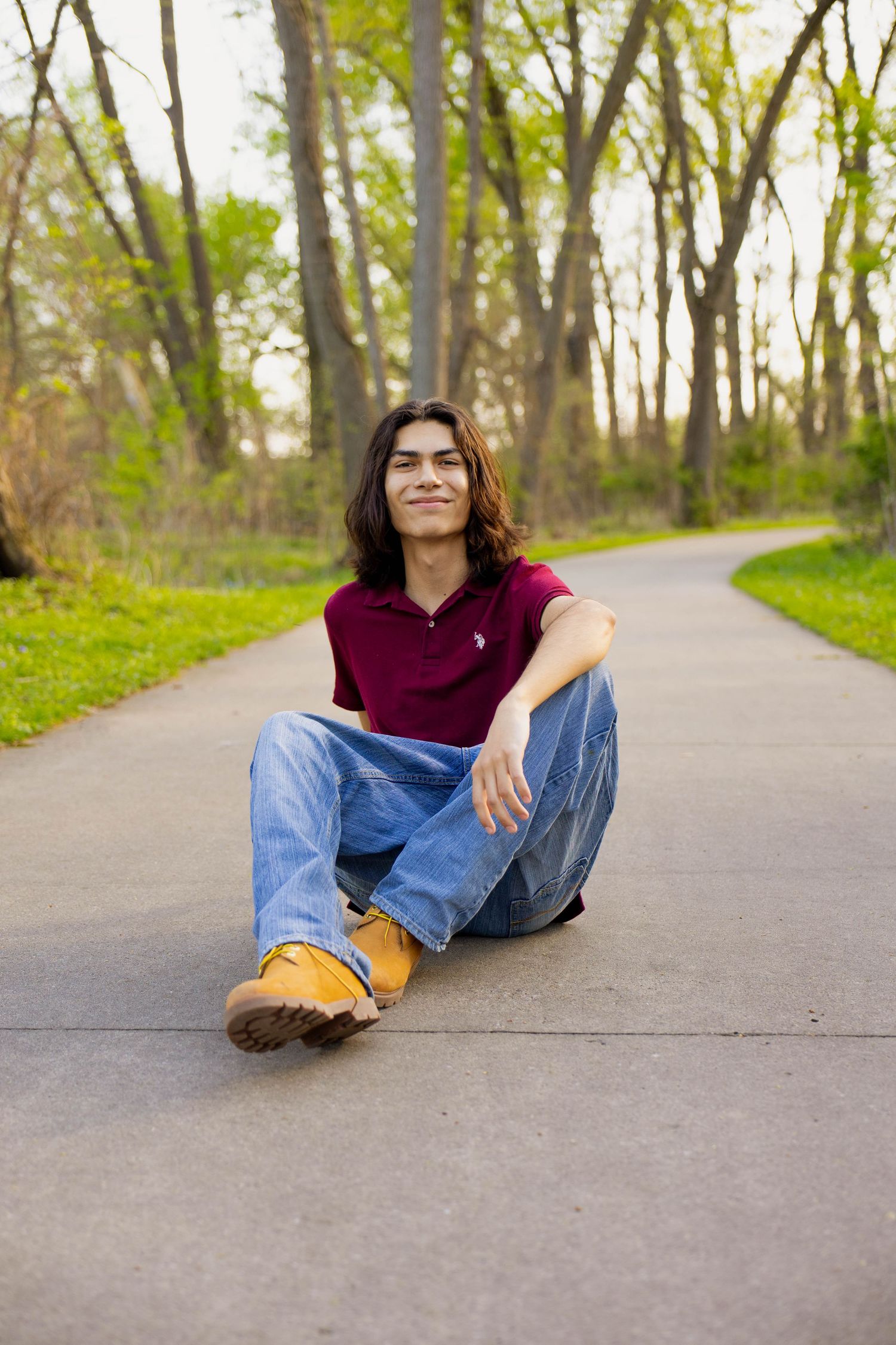 A portrait of a senior boy sitting on a staircase outdoors.