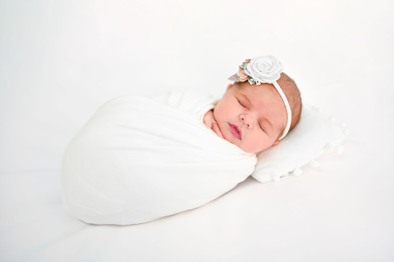 Serene newborn photography series with white backdrop and minimal styling.