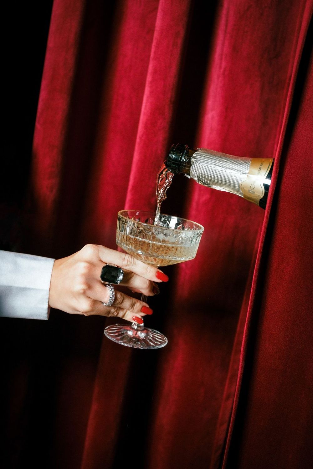 Hands hold champagne glasses against a deep red velvet curtain backdrop in a series of elegant party celebration images.