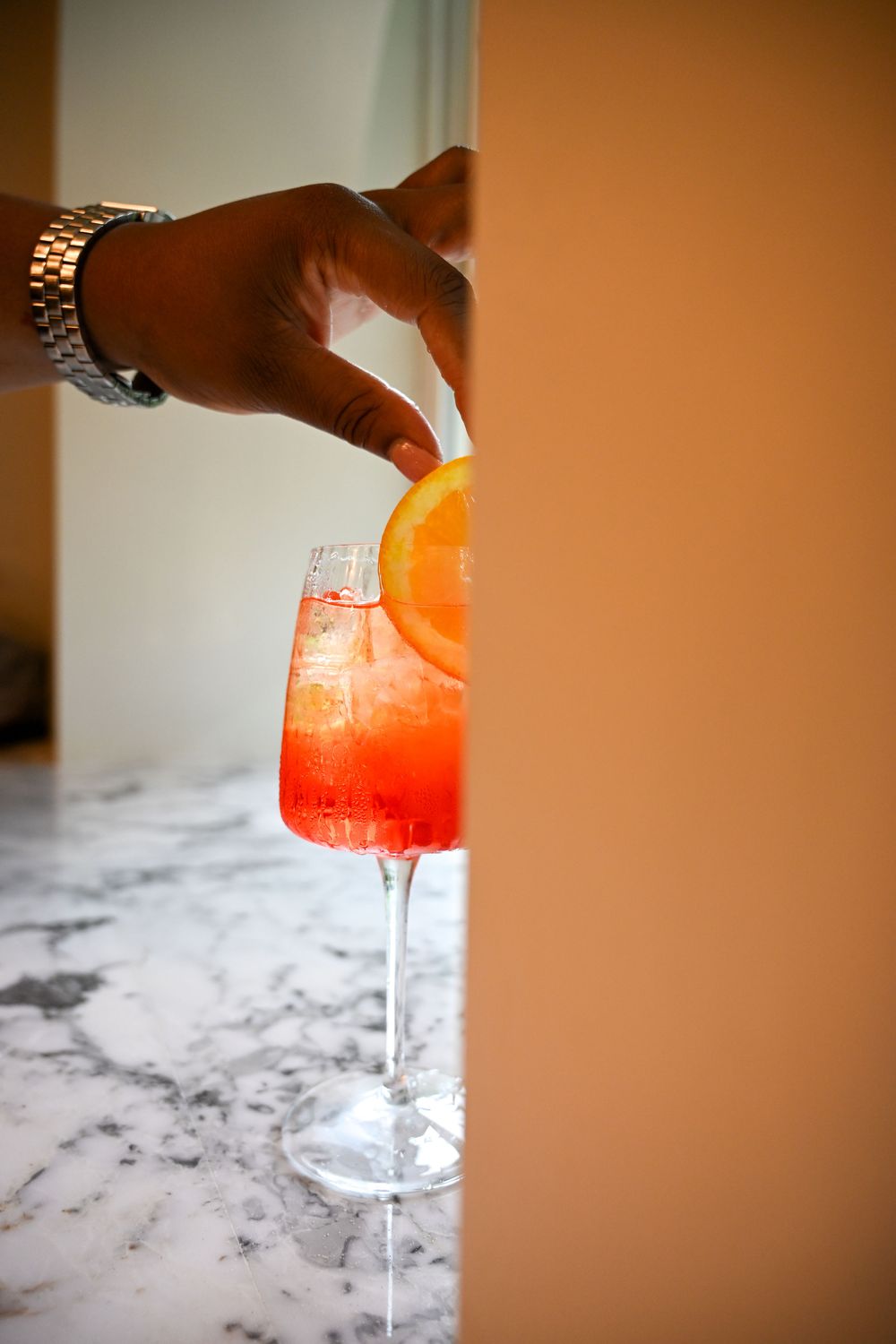 A sequence of photos showing a red and orange cocktail being poured into a glass with a gradient color effect.