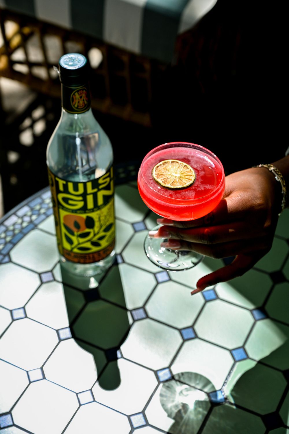 A hand holds a red-capped beverage bottle on a white and blue hexagonal tiled surface in dim lighting.