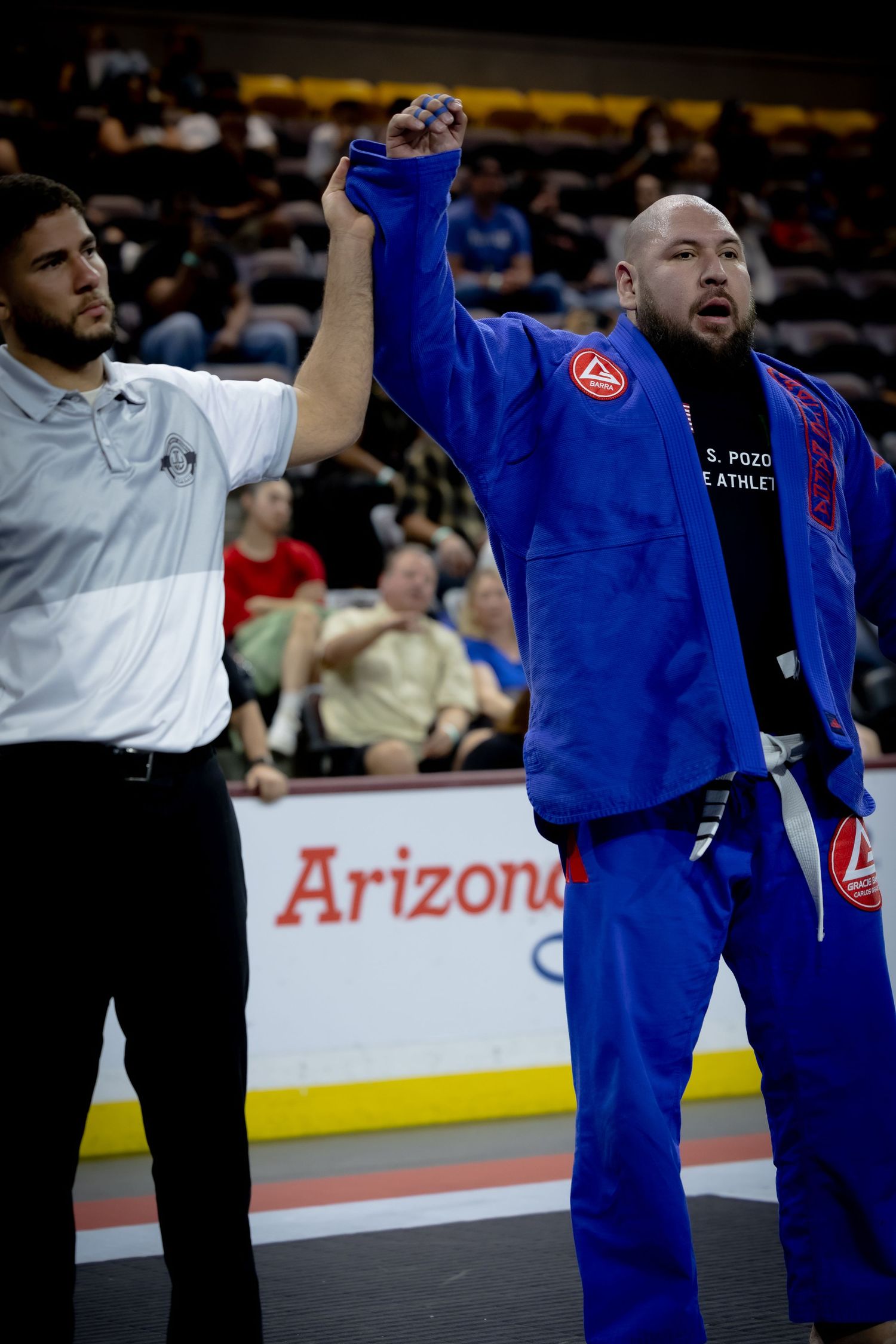 Competitors and referees gather on the mat during a martial arts competition event.