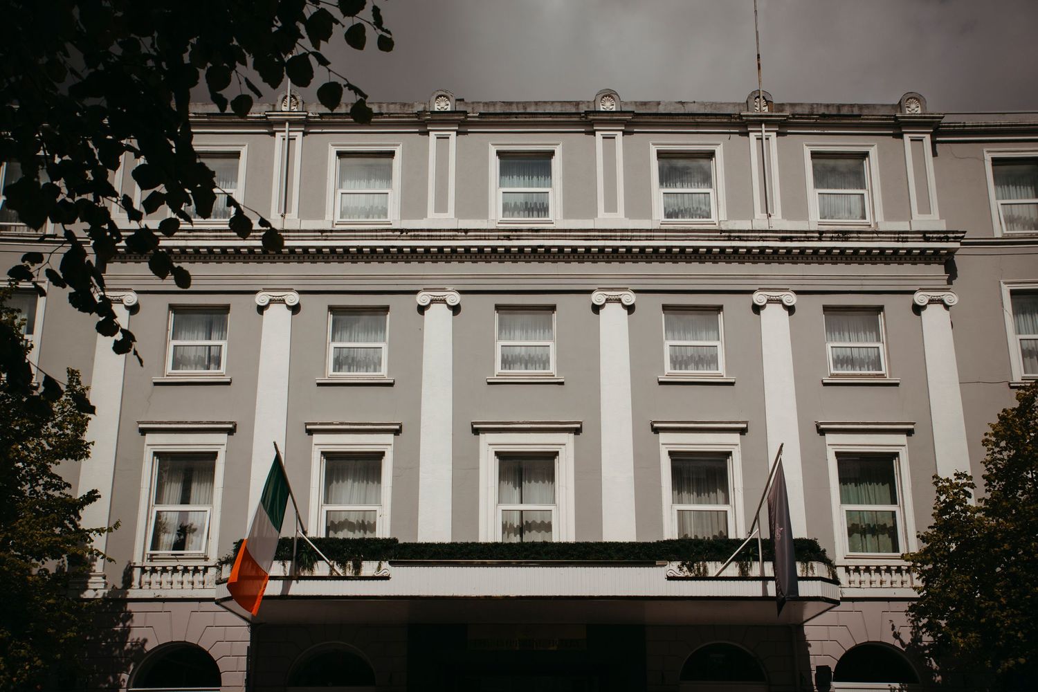 Classic hotel facade with white columns and rows of windows against a dark dramatic sky.