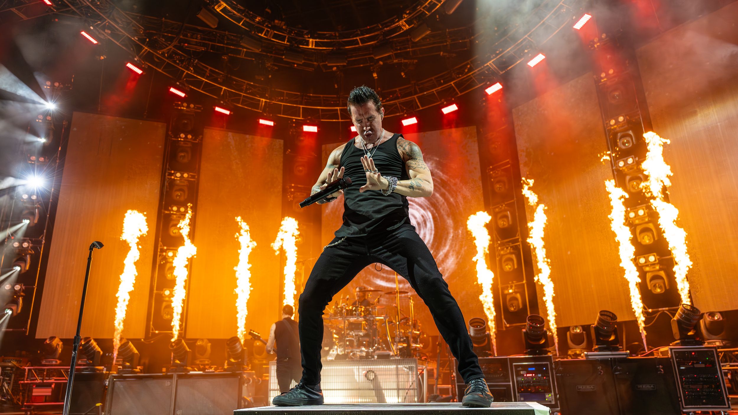 Rock concert performance with pyrotechnic flames and dramatic orange stage lighting.