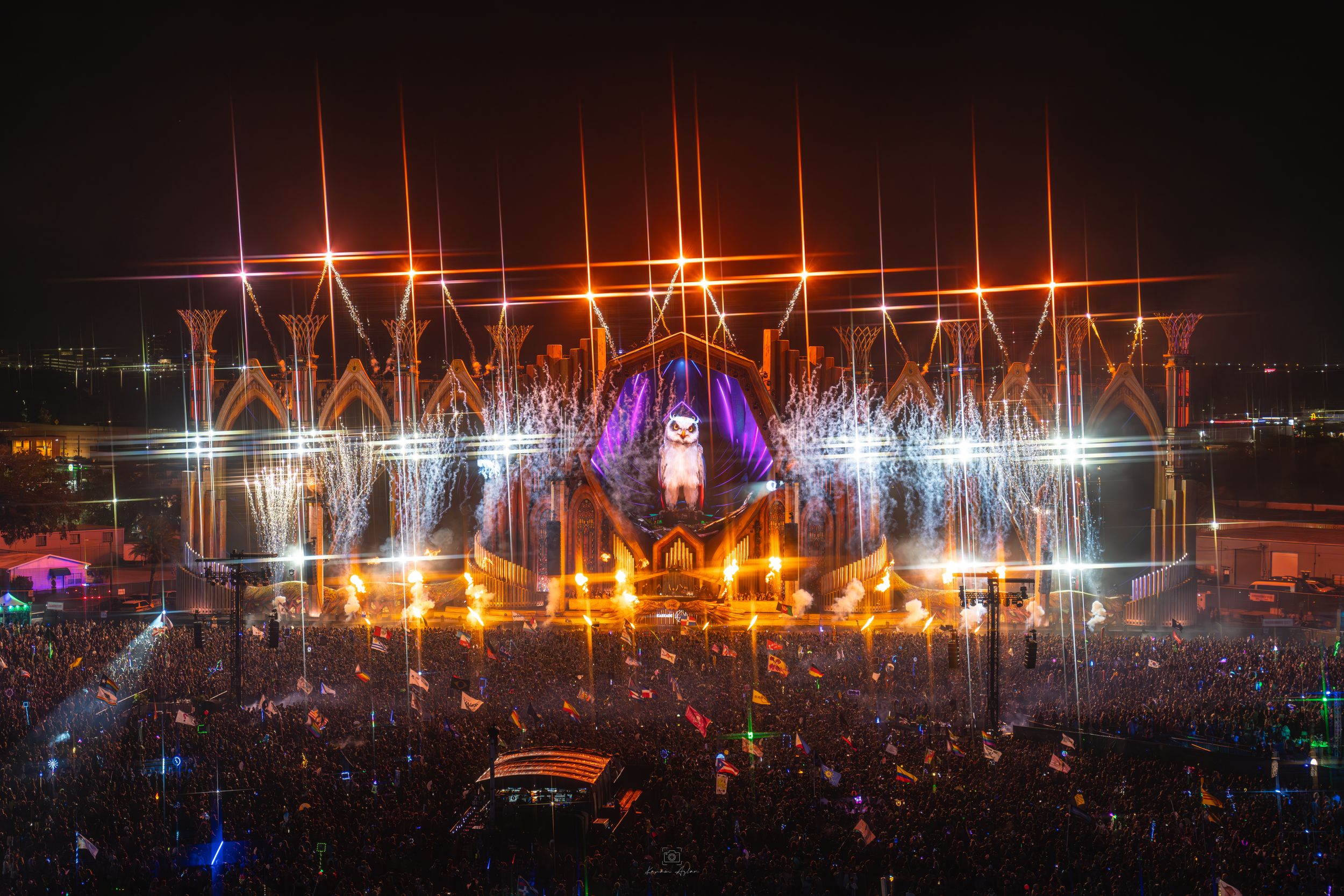 Panoramic view of festival grounds with illuminated stages and lighting rigs stretching across the horizon.