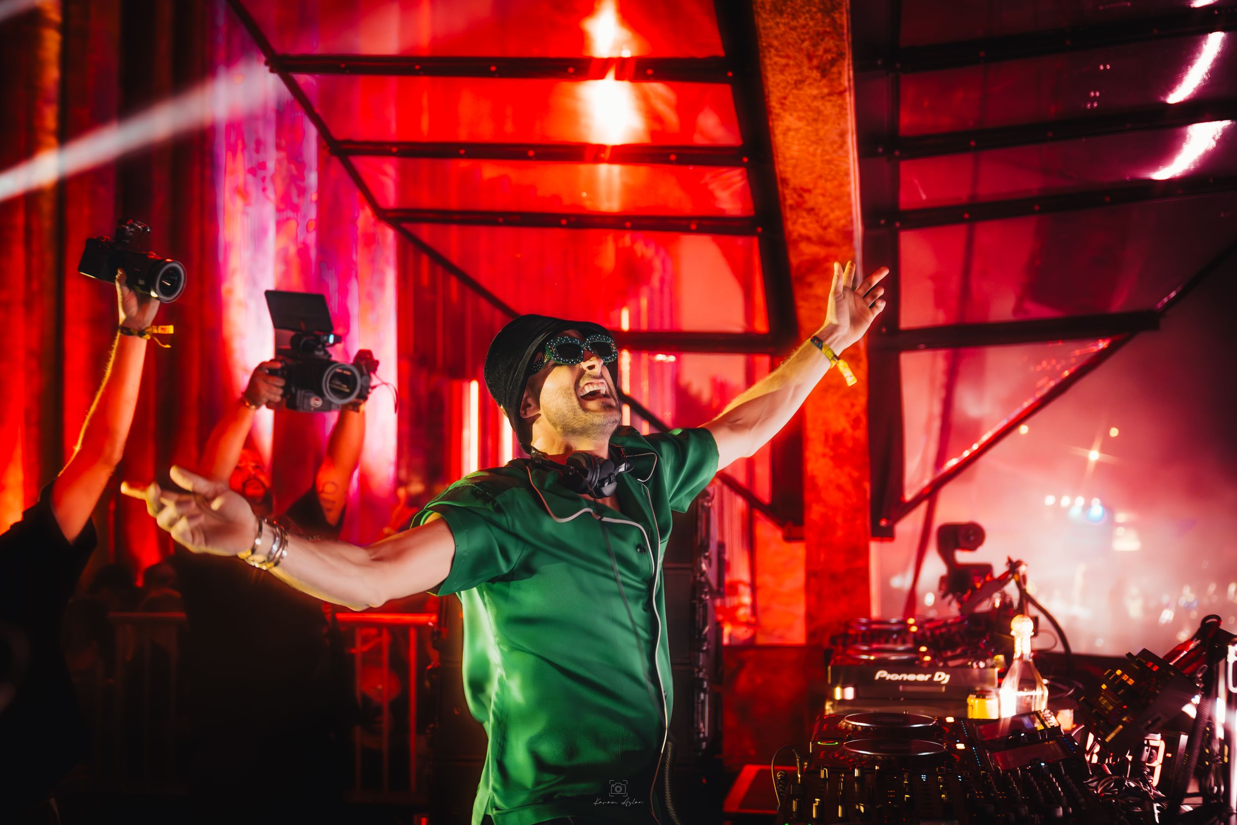 Music festival stage bathed in intense red lighting with performers creating an energetic atmosphere.