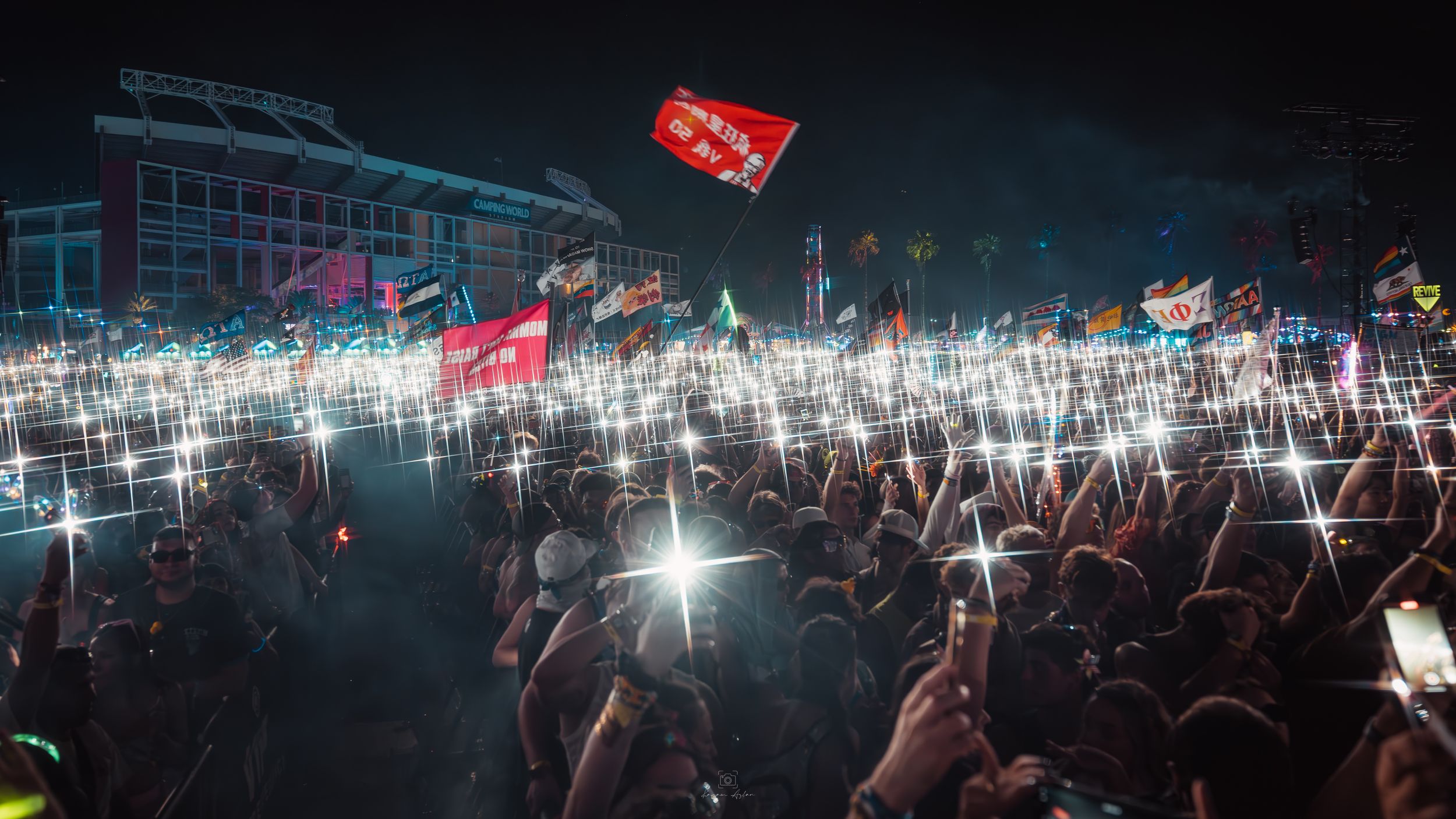 Concert crowd silhouetted against bright stage lights during nighttime performance.