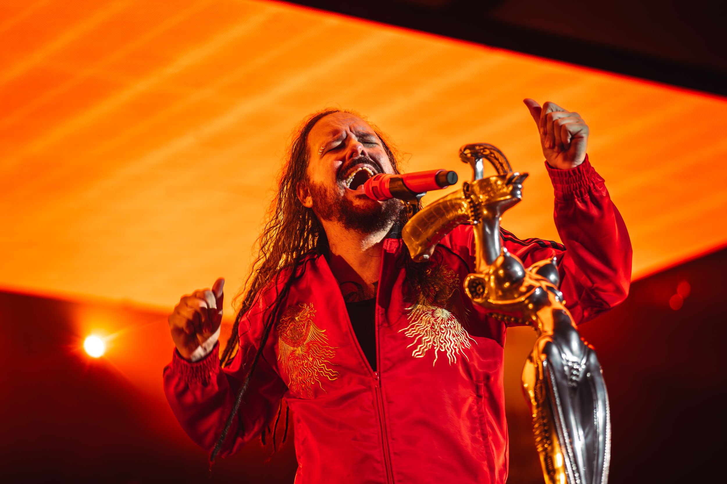 Dramatic concert performance illuminated by intense orange stage lighting and fog effects.