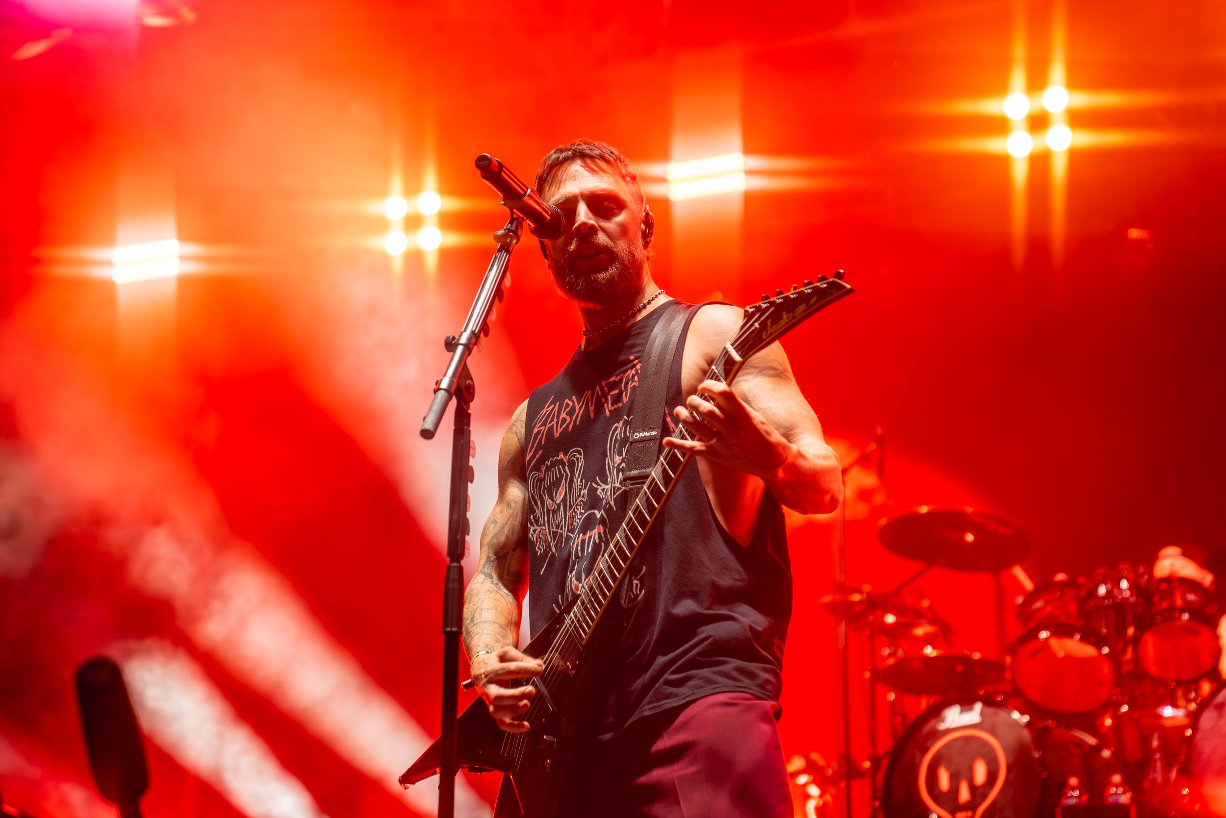 Rock musician performing with guitar against bright red stage lighting.