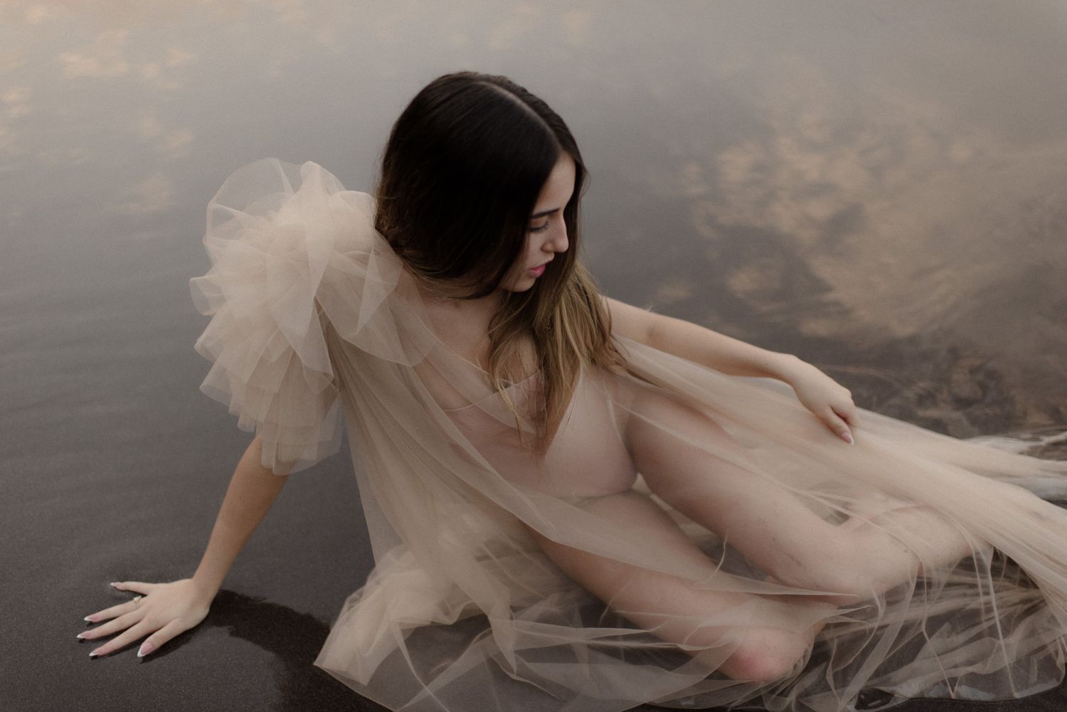 Artistic portrait with flowing fabric creating dreamy movement against muted background.