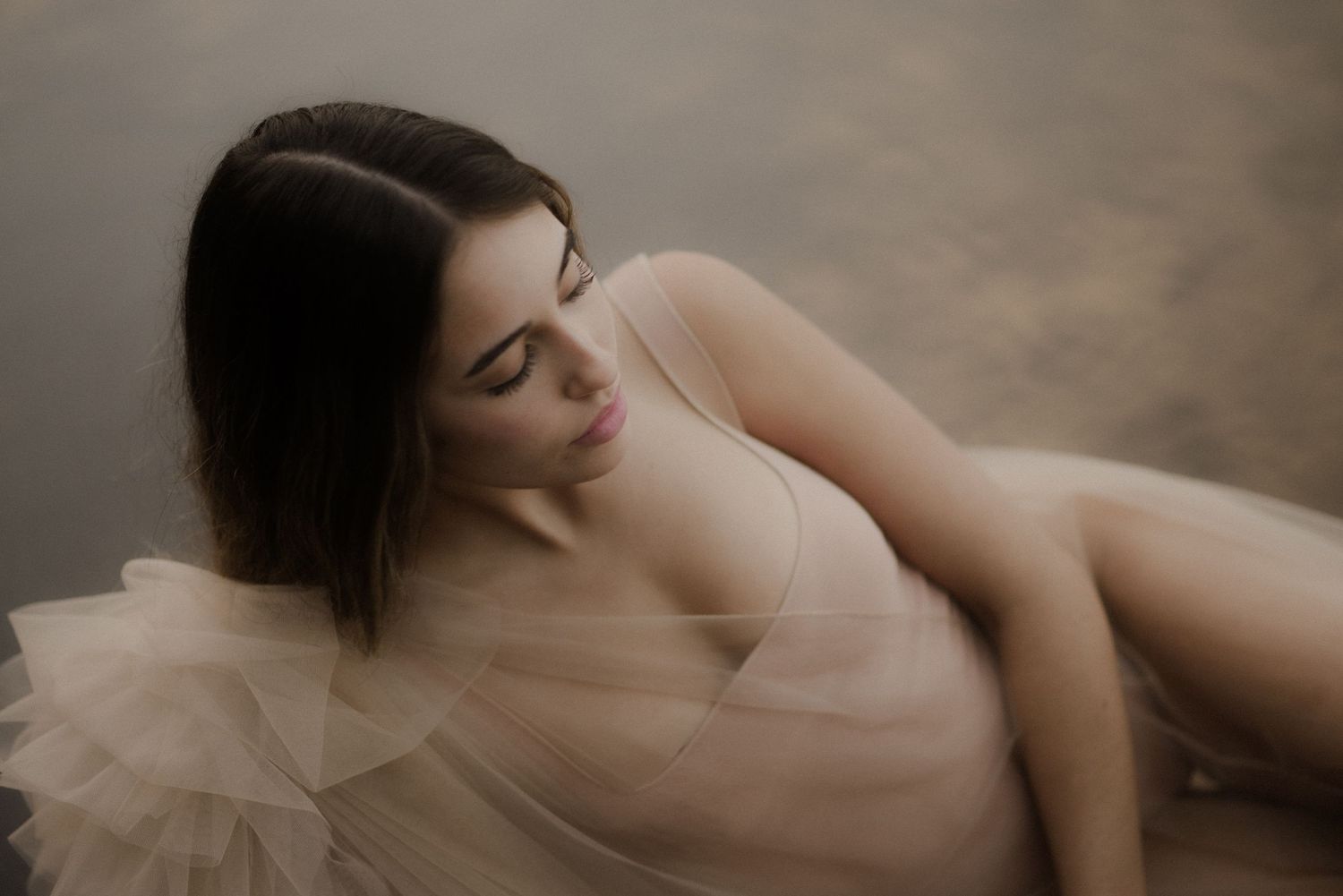 Dreamy boudoir photography with soft lighting showcasing delicate curves and tulle fabric.