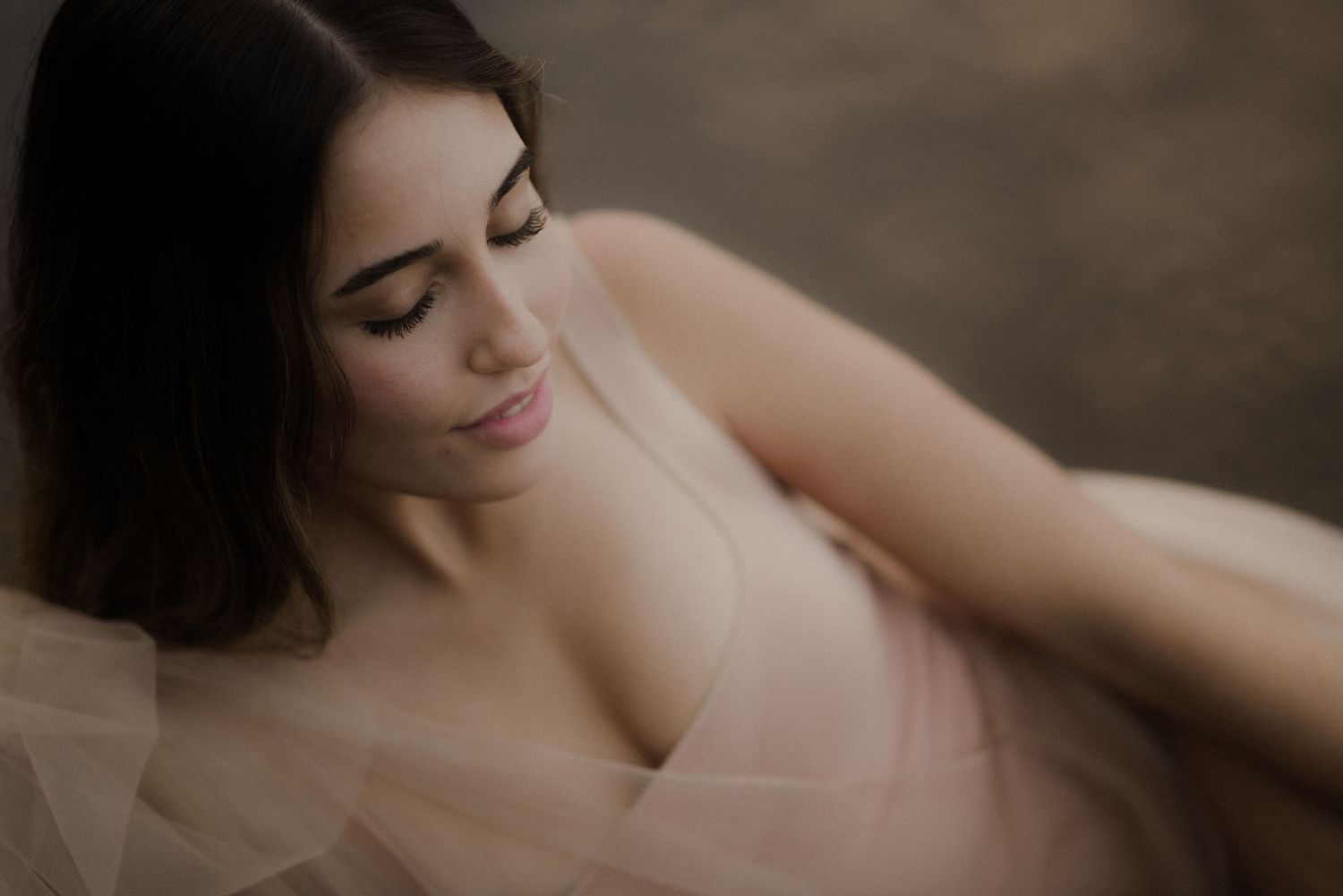 Romantic bridal boudoir portrait with soft lighting and delicate lace details in muted earth tones.