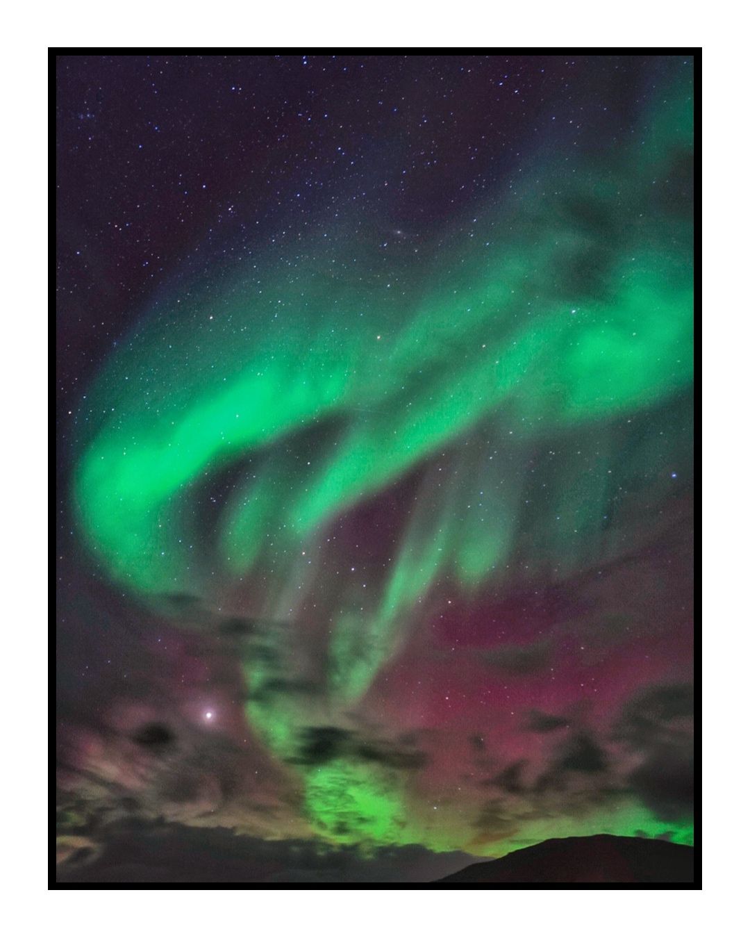 Vibrant green and purple aurora borealis dancing across the night sky in Iceland.