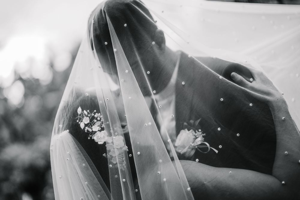 A romantic wedding first look moment captured in black and white with falling petals in the background.