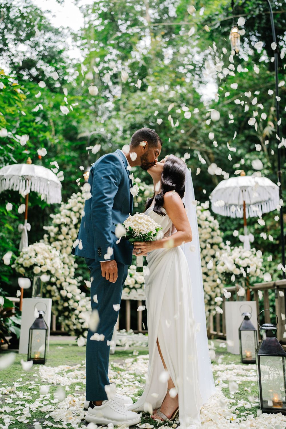 Wedding ceremony setup with lanterns and white petals scattered on a garden path.