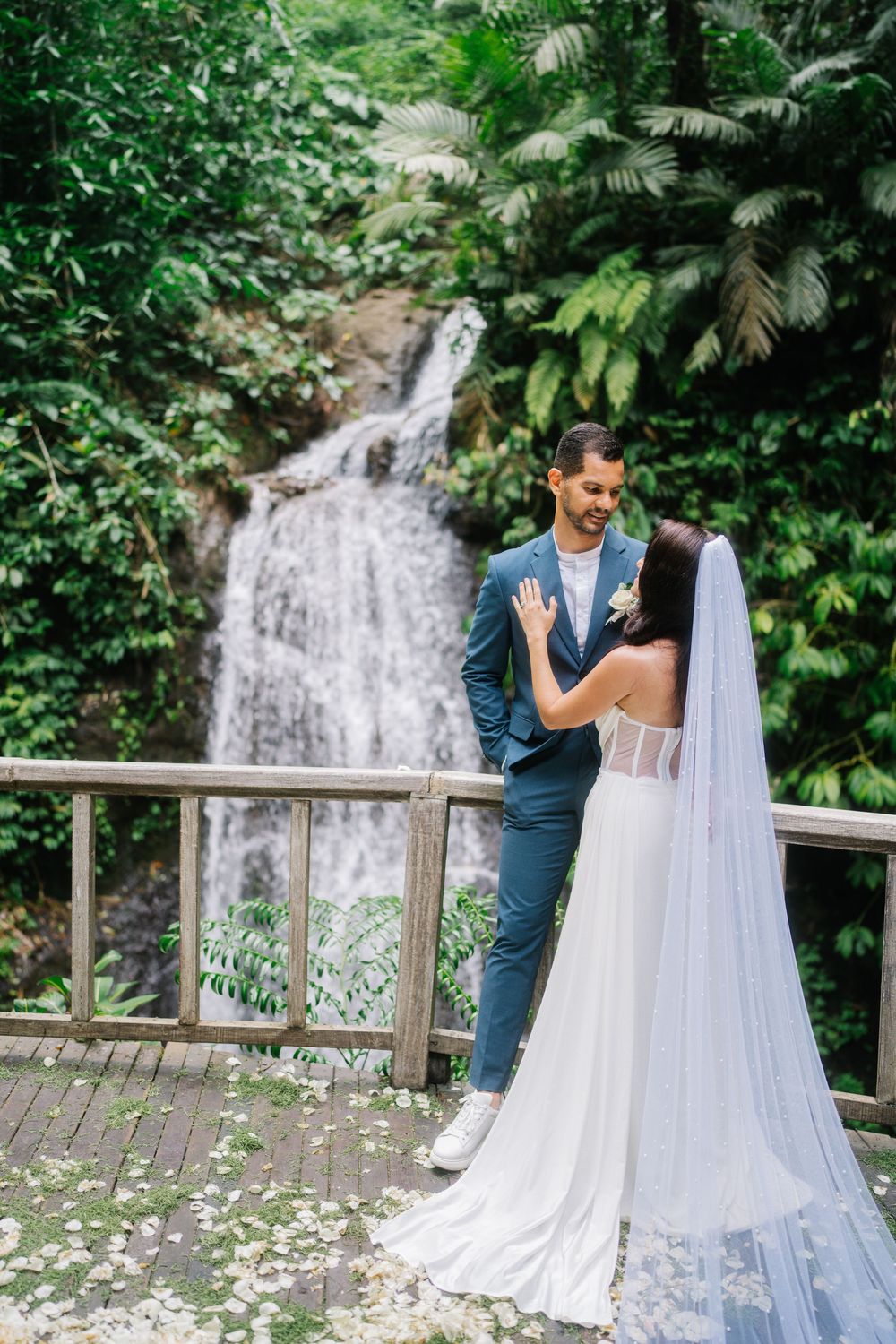 Romantic wedding portraits with a cascading waterfall backdrop and wooden deck railing.