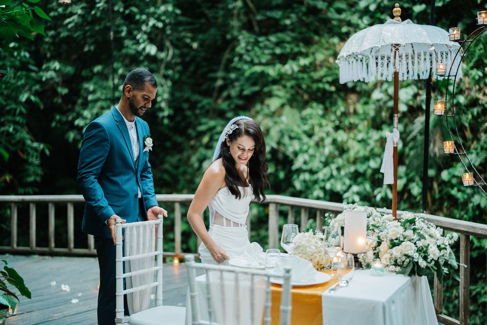 An elegant outdoor wedding reception setup with white chairs and floral arrangements.