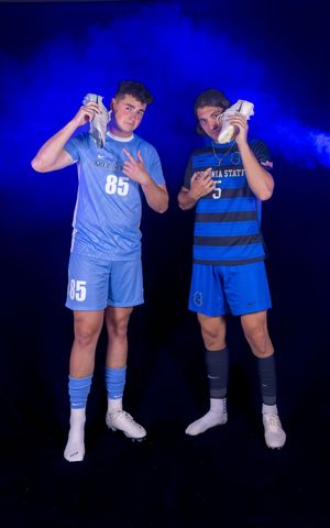 Athletes in numbered blue uniforms pose with soccer balls under dramatic studio lighting.