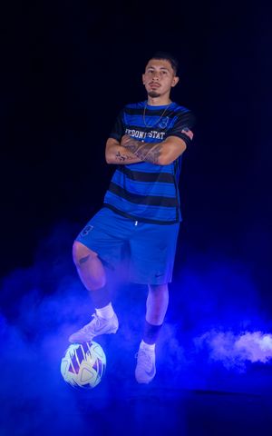 Soccer players demonstrate ball control moves with dramatic low fog effects and blue lighting.