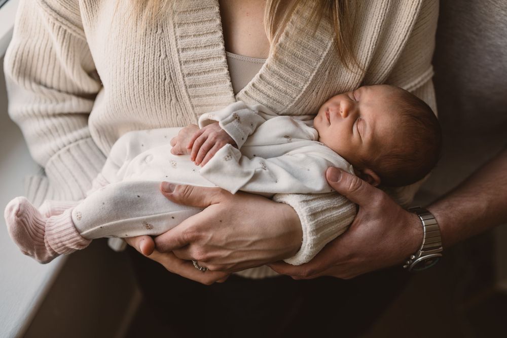 A tender moment showing a newborn baby being cradled on her parents' arms.