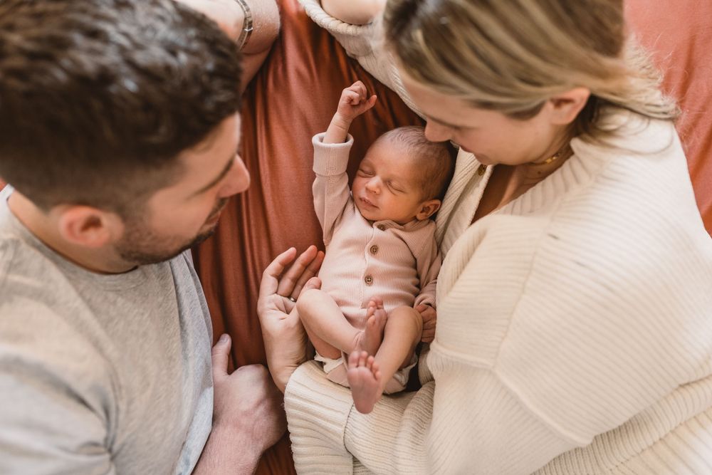 A tender moment showing parents holding a newborn baby in a warm photograph.