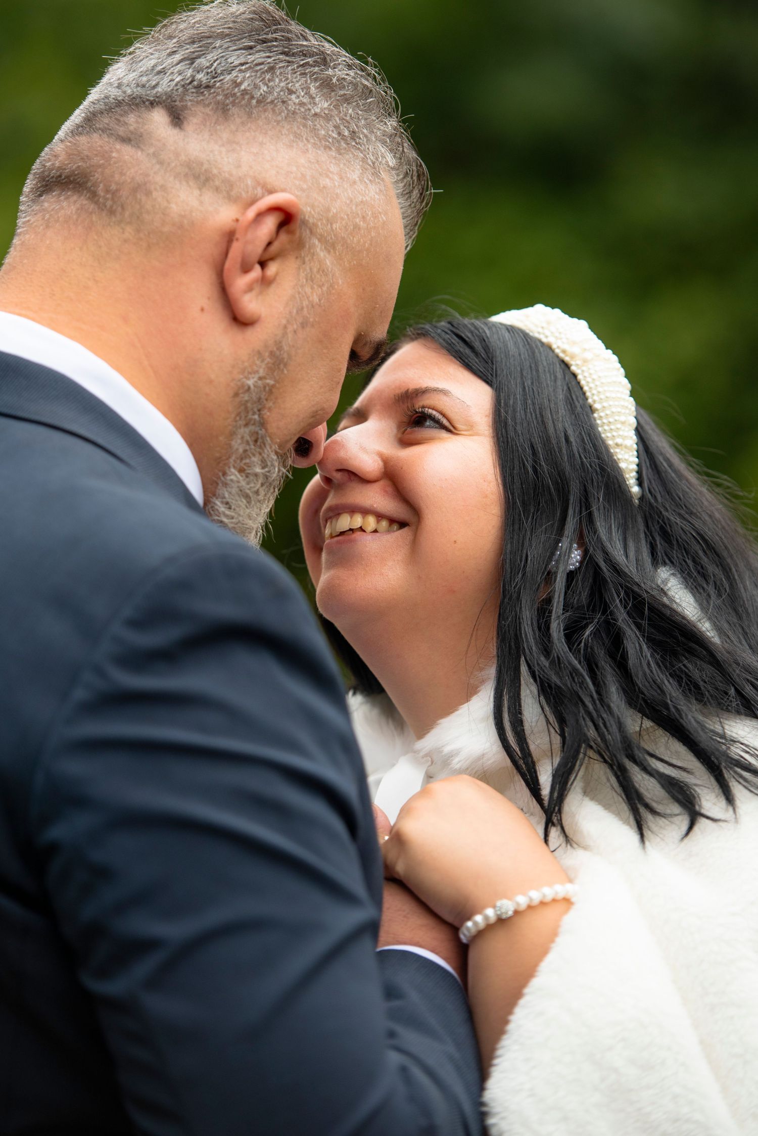 Close-up of romantic wedding couple about to kiss outdoors.
