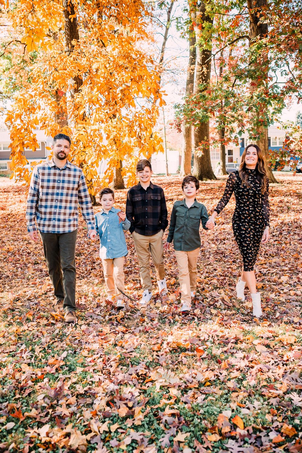 Group of people walking through vibrant autumn leaves in a wooded area during fall season.