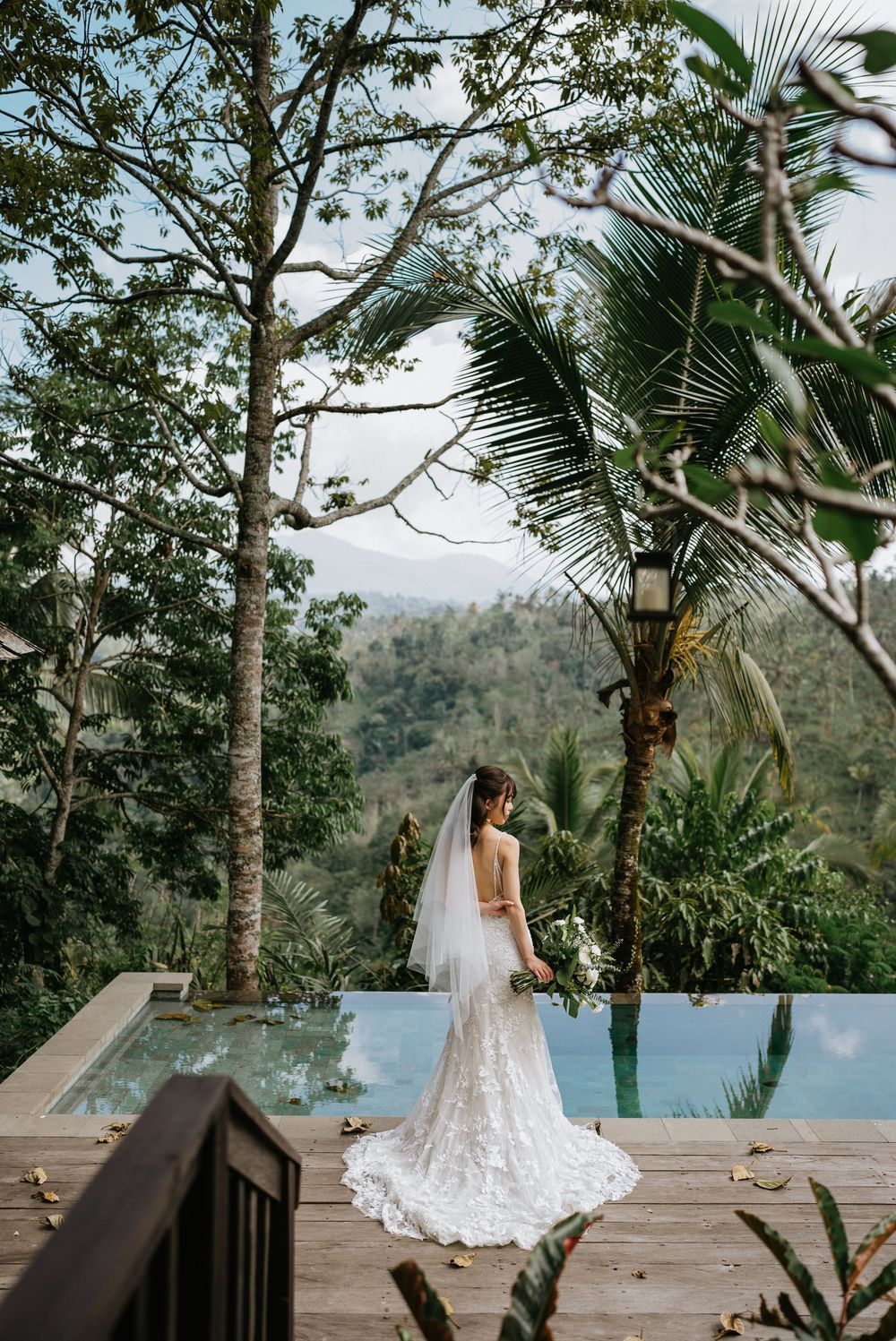 A scenic deck overlooking mountains with palm trees and tropical foliage.