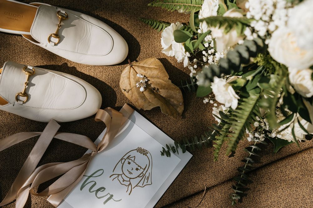 Wedding place cards with hand-drawn illustrations arranged with white flowers and greenery.